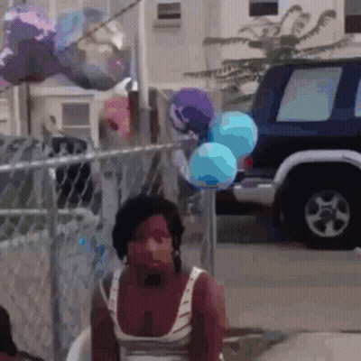 Woman Sitting In Front Of Fence With Balloons GIF