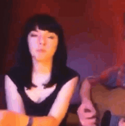 Woman Sitting In Front Of Man Playing Guitar In Dark Room GIF