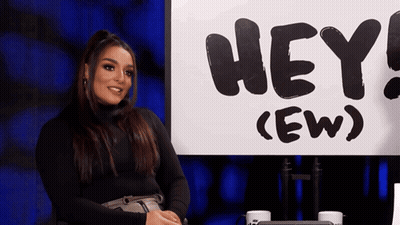Woman Sitting In Front Of Sign Saying Hey GIF