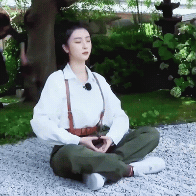Woman Sitting In Lotus Position On Gravel GIF