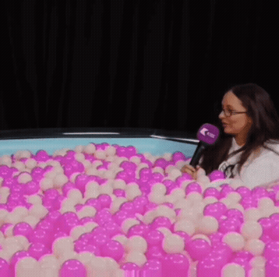 Woman Sitting In Pink And White Ball Pit GIF