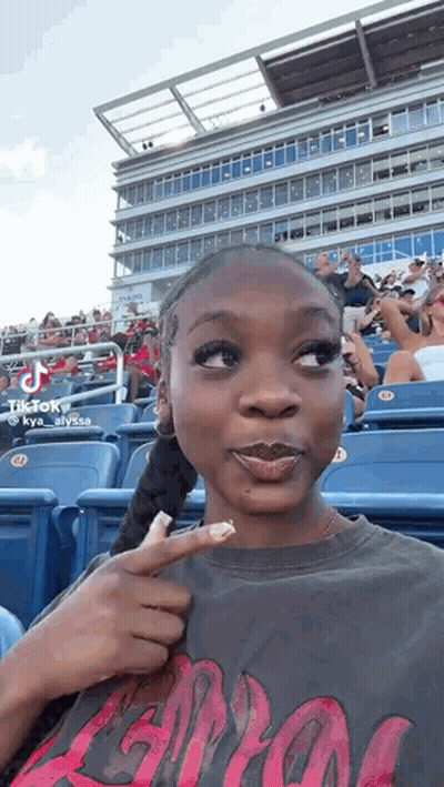 Woman Sitting In Stands Pointing At Herself GIF