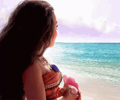 Woman Sitting On Beach Holding Seashell GIF