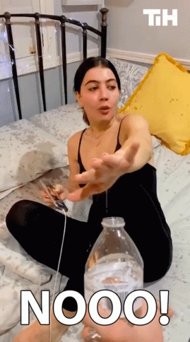 Woman Sitting On Bed Holding Phone And Nooo Water Bottle GIF