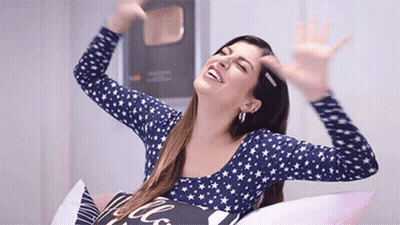 Woman Sitting On Bed Smiling Arms Outstretched GIF