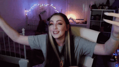 Woman Sitting On Bed With Arms Outstretched And Letter A On Shirt GIF