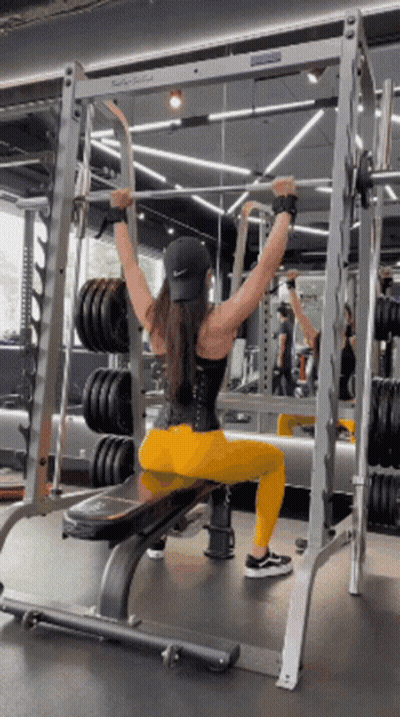 Woman Sitting On Bench In Gym Holding Barbell Overhead GIF