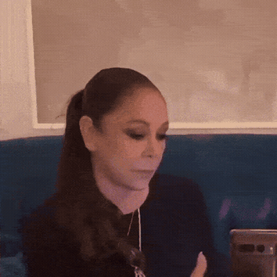 Woman Sitting On Blue Couch Looking At Cell Phone GIF