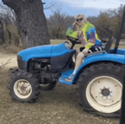 Woman Sitting On Blue Tractor In Field GIF