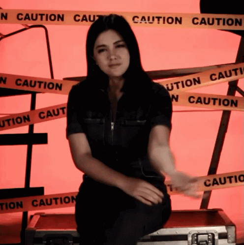 Woman Sitting On Briefcase With Caution Tape GIF