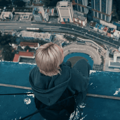 Woman Sitting On Building Edge Overlooking City GIF