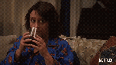 Woman Sitting On Couch Drinking With Netflix Logo GIF