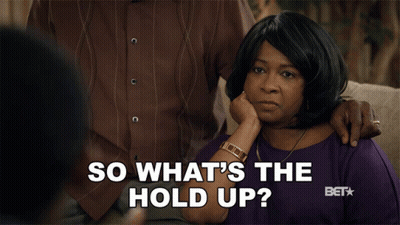 Woman Sitting On Couch Hand On Chin Saying So What's The Hold Up GIF
