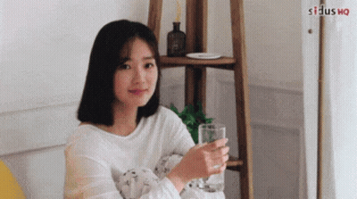 Woman Sitting On Couch Holding Glass Of Water GIF