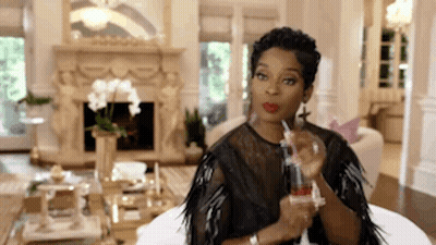 Woman Sitting On Couch Holding Perfume Bottle GIF