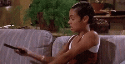 Woman Sitting On Couch Holding Remote And Smoking GIF