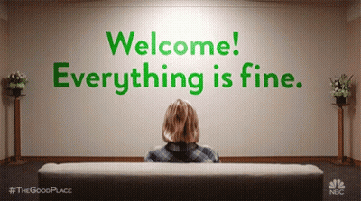 Woman Sitting on Couch in Front of Welcome Everything Is Fine Wall