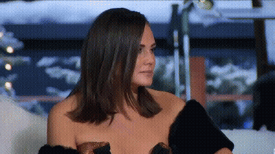 Woman Sitting On Couch In Fur Coat And Strapless Top GIF