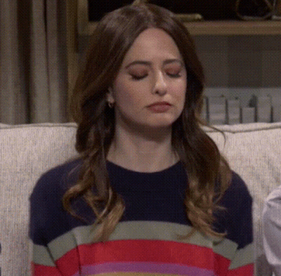 Woman Sitting On Couch In Striped Sweater Making Funny Face GIF