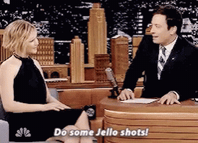 Woman Sitting On Couch Talking To Man In Suit Saying Do Some Jello Shots GIF