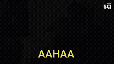 Woman Sitting On Couch With Aahaa In Yellow Letters GIF