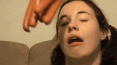 Woman Sitting On Couch With Eyes Closed Being Hit By Sausage GIF