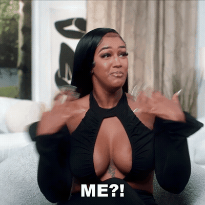 Woman Sitting On Couch With Hands In Air Saying Me GIF