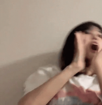 Woman Sitting On Couch With Mouth Open And Hands Up GIF