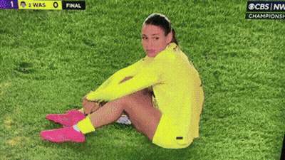 Woman Sitting On Grass In Front Of CBS NW Championship Game GIF