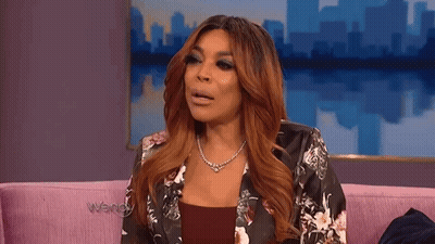 Woman Sitting On Pink Couch In Floral Jacket GIF