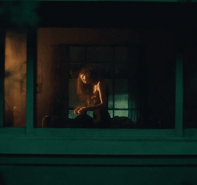 Woman Sitting On Porch Looking Out Window At Night GIF