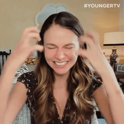 Woman Smiling And Covering Ears In Younger TV Shirt GIF