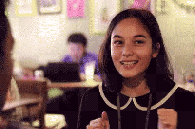 Woman Smiling And Giving Thumbs Up In Cafe GIF