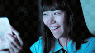 Woman Smiling At Phone In Dark GIF