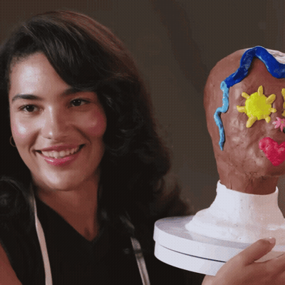 Woman Smiling Holding Sculpture Of Head GIF
