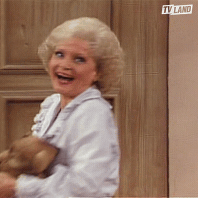 Woman Smiling Holding Teddy Bear In Front Of TV Land Door GIF