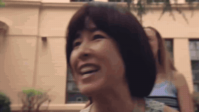 Woman Smiling In Front Of Building With Another Woman Looking On GIF