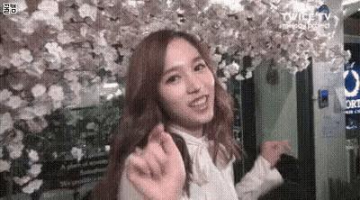 Woman Smiling In Front Of Flower Wall GIF
