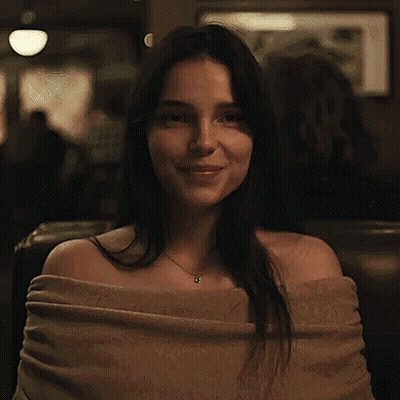 Woman Smiling In Restaurant With Sweater And Necklace GIF