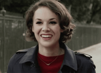 Woman Smiling In Trench Coat And Necklace GIF