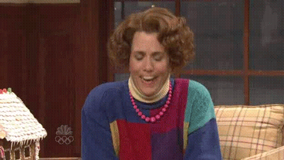 Woman Smiling On Couch In Front Of Gingerbread House GIF