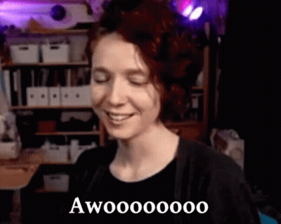 Woman Smiling With Eyes Closed In Room With Shelf GIF