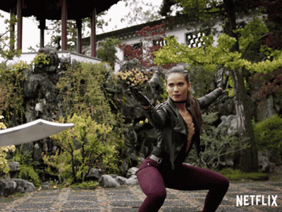 Woman Squatting With Sword In Front Of Netflix Sign GIF