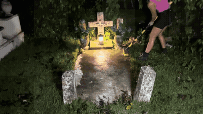 Woman Standing At Grave With Cross And Candle GIF