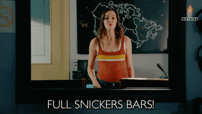 Woman Standing Before Full Snickers Bars GIF