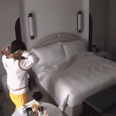 Woman Standing By Bed With White Blanket GIF