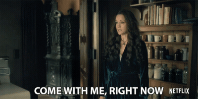 Woman Standing By Bookshelf Saying Come With Me GIF