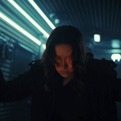 Woman Standing in Dark Room With Lights Behind Her