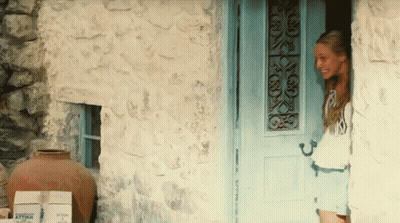 Woman Standing In Front Of Blue Door With Boxes Saying Attar GIF
