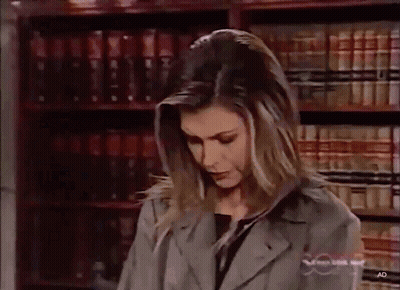 Woman Standing In Front Of Bookshelf With Ad GIF